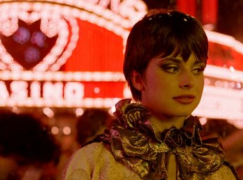 Movie still from “One from the Heart” (1981), directed by Francis Ford Coppola – A woman with a bow tie standing in front of a neon sign; Close Up shot, Low angle