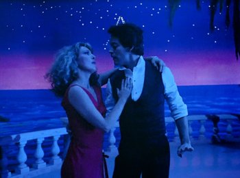 Movie still from “One from the Heart” (1981), directed by Francis Ford Coppola – A man and a woman are dancing in front of a night sky; Medium shot, Low angle