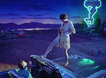 Movie still from “One from the Heart” (1981), directed by Francis Ford Coppola – A woman standing on top of a car next to a boy; Wide shot, Low angle