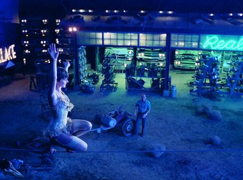 Movie still from “One from the Heart” (1981), directed by Francis Ford Coppola – A man and a woman are standing next to each other in a garage; Wide shot, Low angle