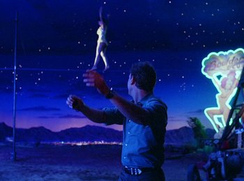 Movie still from “One from the Heart” (1981), directed by Francis Ford Coppola – A man in a blue shirt is playing with an object in the air; Wide shot, Low angle