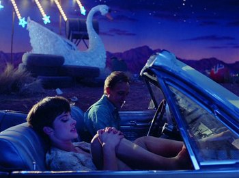 Movie still from “One from the Heart” (1981), directed by Francis Ford Coppola – A man and a woman sitting in the back of a car; Wide shot, High angle