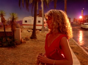 Movie still from “One from the Heart” (1981), directed by Francis Ford Coppola – A woman in a red dress standing in front of palm trees; Wide shot, Over the shoulder angle