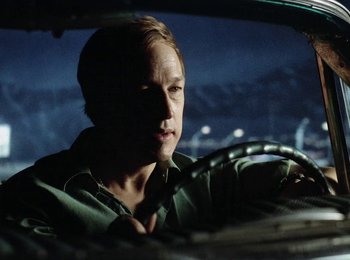 Movie still from “One from the Heart” (1981), directed by Francis Ford Coppola – A man sitting in the drivers seat of a car at night; Close Up shot, Over the shoulder angle