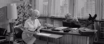 Movie still from “One, Two, Three” (1961), directed by Billy Wilder – Two people sitting at a desk in an office setting; Medium shot, High angle