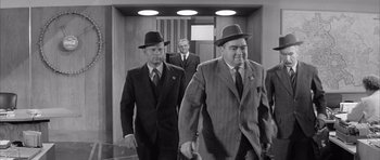 Movie still from “One, Two, Three” (1961), directed by Billy Wilder – A black and white photo of men in suits and hats; Medium shot, Low angle