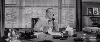 Movie still from “One, Two, Three” (1961), directed by Billy Wilder – An older man sitting at a desk talking on the phone; Medium shot, Low angle