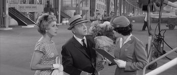 Movie still from “One, Two, Three” (1961), directed by Billy Wilder – An old photo of a man and two women; Medium shot, Over the shoulder angle