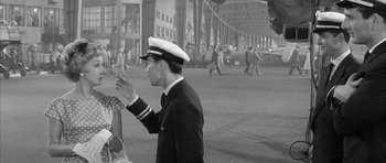 Movie still from “One, Two, Three” (1961), directed by Billy Wilder – A man in a sailor's uniform waving to a woman; Medium shot, High angle