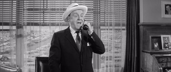 Movie still from “One, Two, Three” (1961), directed by Billy Wilder – An older man wearing a hat talking on a phone; Medium shot, Low angle