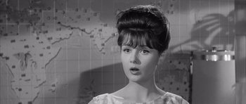 Movie still from “One, Two, Three” (1961), directed by Billy Wilder – A young woman with a large hair bun and bangs; Close Up shot, Over the shoulder angle