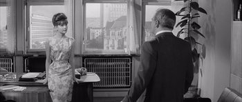 Movie still from “One, Two, Three” (1961), directed by Billy Wilder – An older man and woman looking out of a window; Medium shot, Over the shoulder angle