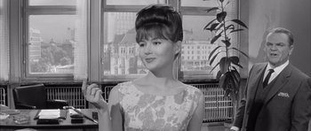 Movie still from “One, Two, Three” (1961), directed by Billy Wilder – A young woman with a high bun in front of a window; Close Up shot, Low angle