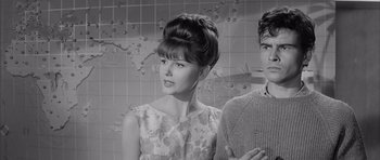 Movie still from “One, Two, Three” (1961), directed by Billy Wilder – A woman with a high bun standing next to a young man; Medium shot, Over the shoulder angle