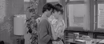 Movie still from “One, Two, Three” (1961), directed by Billy Wilder – A couple of people standing next to each other in front of a window; Medium shot, High angle