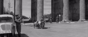 Movie still from “One, Two, Three” (1961), directed by Billy Wilder – A man riding a motorcycle with a sidecar; Wide shot, Low angle