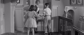 Movie still from “One, Two, Three” (1961), directed by Billy Wilder – A black and white photo of a woman and two young children; Medium shot, Over the shoulder angle