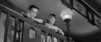 Movie still from “One, Two, Three” (1961), directed by Billy Wilder – Two young children standing on the railing of a staircase; Medium shot, Low angle
