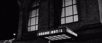 Movie still from “One, Two, Three” (1961), directed by Billy Wilder – A black - and - white photo of a grand hotel sign; Close Up shot, Low angle