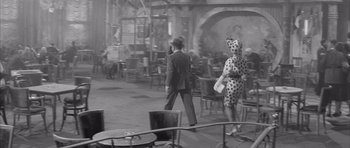 Movie still from “One, Two, Three” (1961), directed by Billy Wilder – A man and a woman walking through a restaurant; Wide shot, High angle