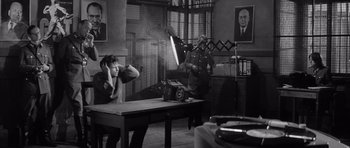 Movie still from “One, Two, Three” (1961), directed by Billy Wilder – A man in a room with a camera and a microphone; Wide shot, High angle
