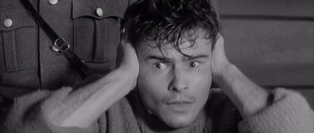 Movie still from “One, Two, Three” (1961), directed by Billy Wilder – A black - and - white photo of a man with his hands behind his head; Close Up shot, High angle