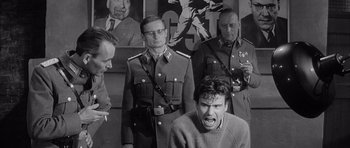 Movie still from “One, Two, Three” (1961), directed by Billy Wilder – A group of men standing next to each other in front of a painting; Medium shot, Over the shoulder angle