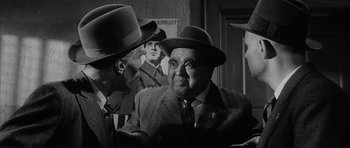 Movie still from “One, Two, Three” (1961), directed by Billy Wilder – A black and white photo of two men wearing hats; Medium shot, Over the shoulder angle