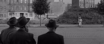 Movie still from “One, Two, Three” (1961), directed by Billy Wilder – A black and white photo of a man in a hat; Wide shot, Over the shoulder angle