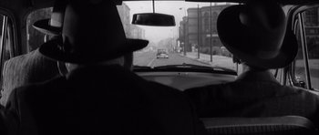 Movie still from “One, Two, Three” (1961), directed by Billy Wilder – A black and white photo of a man driving a car; Close Up shot, Over the shoulder angle