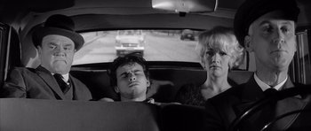 Movie still from “One, Two, Three” (1961), directed by Billy Wilder – A man and a woman in the back seat of a car; Medium shot, High angle