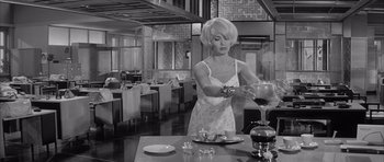 Movie still from “One, Two, Three” (1961), directed by Billy Wilder – A black and white photo of a woman pouring a glass of red wine; Medium shot, Low angle