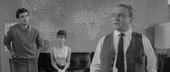 Movie still from “One, Two, Three” (1961), directed by Billy Wilder – An older man and a young woman in front of a map; Medium shot, Over the shoulder angle