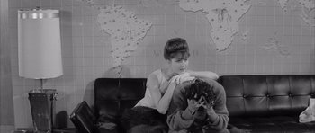 Movie still from “One, Two, Three” (1961), directed by Billy Wilder – A woman sitting on a couch next to a man holding a camera; Medium shot, High angle