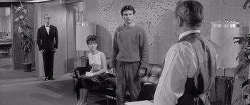 Movie still from “One, Two, Three” (1961), directed by Billy Wilder – A man and a woman standing next to each other in a room; Medium shot, Over the shoulder angle