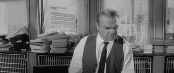 Movie still from “One, Two, Three” (1961), directed by Billy Wilder – An older man wearing a vest and a tie in an office setting; Medium shot, Over the shoulder angle