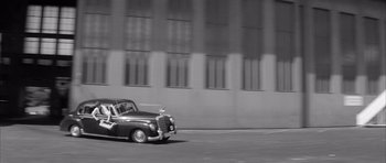 Movie still from “One, Two, Three” (1961), directed by Billy Wilder – A black and white photo of a car driving down the street; Extreme Wide shot, High angle