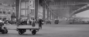 Movie still from “One, Two, Three” (1961), directed by Billy Wilder – A black and white photo of people walking in an industrial area; Extreme Wide shot, High angle