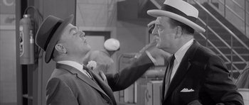 Movie still from “One, Two, Three” (1961), directed by Billy Wilder – A man in a suit and a man in a hat; Medium shot, Over the shoulder angle