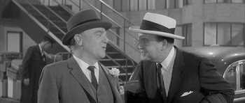 Movie still from “One, Two, Three” (1961), directed by Billy Wilder – A couple of men standing next to each other; Medium shot, Over the shoulder angle