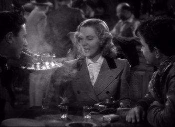 Movie still from “Only Angels Have Wings” (1939), directed by Howard Hawks – An old photo of a woman sitting at a table smoking a cigarette; Medium shot, High angle
