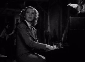 Movie still from “Only Angels Have Wings” (1939), directed by Howard Hawks – A black and white photo of a woman sitting at a piano; Medium shot, Low angle