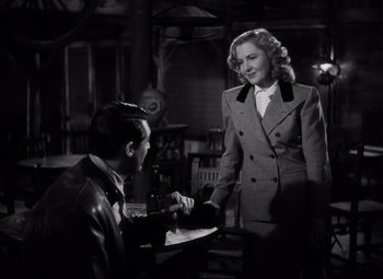 Movie still from “Only Angels Have Wings” (1939), directed by Howard Hawks – A man and a woman are standing at a table; Medium shot, Over the shoulder angle