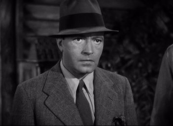 Movie still from “Only Angels Have Wings” (1939), directed by Howard Hawks – A man wearing a suit and a hat in a black and white photo; Close Up shot, High angle