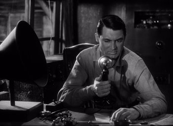 Movie still from “Only Angels Have Wings” (1939), directed by Howard Hawks – A man sitting at a desk holding a microphone; Close Up shot, Low angle