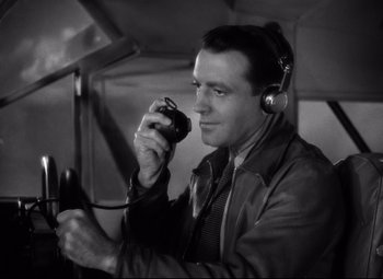 Movie still from “Only Angels Have Wings” (1939), directed by Howard Hawks – A man with headphones on holding a remote control; Close Up shot, Low angle