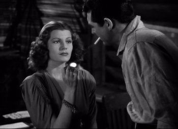 Movie still from “Only Angels Have Wings” (1939), directed by Howard Hawks – A man and a woman standing next to each other holding a cigarette; Medium shot, Over the shoulder angle