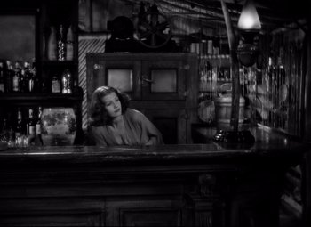 Movie still from “Only Angels Have Wings” (1939), directed by Howard Hawks – A black and white photo of a woman sitting at a bar; Medium shot, High angle