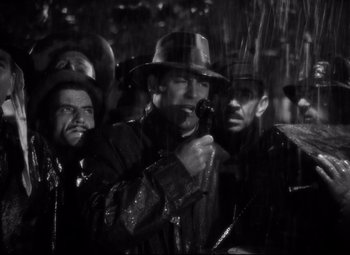 Movie still from “Only Angels Have Wings” (1939), directed by Howard Hawks – A group of men standing next to each other in the rain; Close Up shot, Low angle