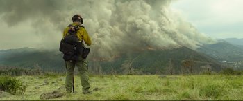 Movie still from “Only the Brave” (2017), directed by Joseph Kosinski – A man standing in a field looking at a forest fire; Wide shot, Low angle